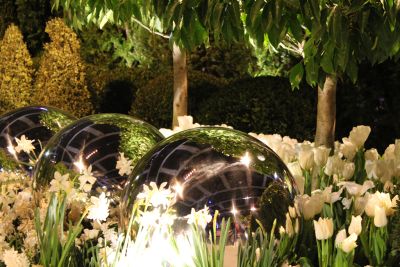 Reflective spheres, trees, and flowers in a garden